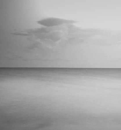 Black and white image of a beach in the evening with a cloudy skyの写真素材