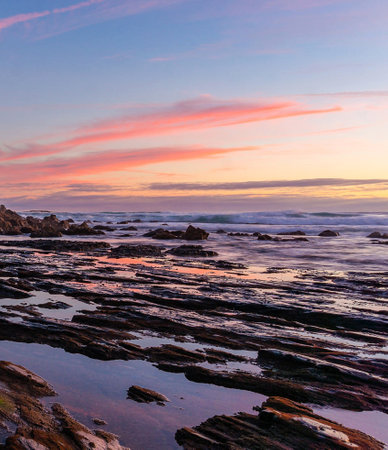Beautiful sunset on the beach with rocks and reflection in water.の写真素材
