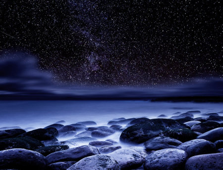 Night sky with stars and milky way over a rocky beach.の写真素材