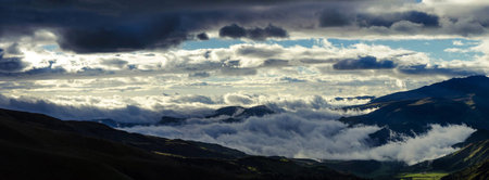 Panoramic view of the mountains with clouds and blue sky.