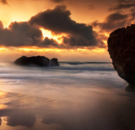 Beautiful sunset over the sea with clouds and rocks in the foregroundの写真素材