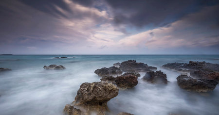 Long exposure seascape with rocks and waves at sunset, Thailand