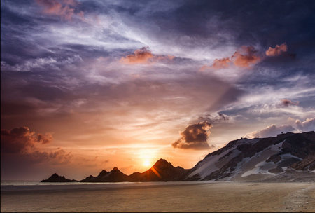 Beautiful sunset at the beach with mountains in the background. Toned.の写真素材