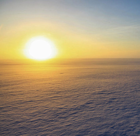 sunset over the sea in winter with snowflakes and sunの写真素材