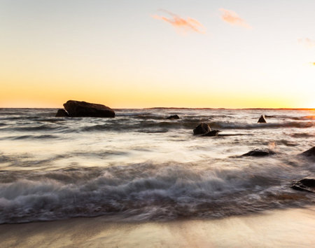 Beautiful sunset on the beach with rocks in the foreground. Toned.の写真素材