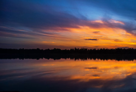 Beautiful sunset over the lake. Colorful clouds reflected in the water.