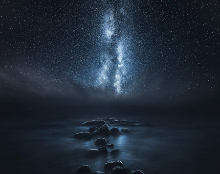 Milky way over the sea with rocks and stars in the skyの写真素材