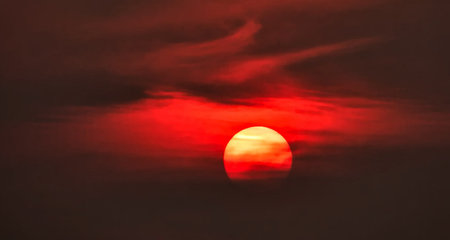 Sunset in the sky with clouds and a red sun on the horizonの写真素材