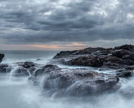 Long exposure of rocks in the ocean with a stormy sky.の写真素材