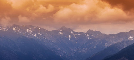 panoramic view of snow-capped mountain peaks at sunsetの写真素材