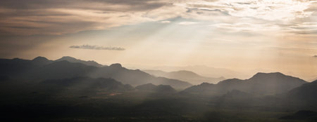 Sunset over the mountains with clouds and sunbeams in the background
