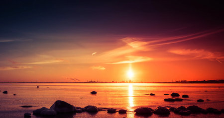 beautiful sunset over the sea with stones on the shore, tonedの写真素材