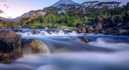Long exposure of a waterfall flowing over rocks in the rainforest at sunriseの写真素材