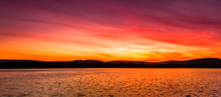 Beautiful sunset on the lake with mountains in the background, long exposureの写真素材