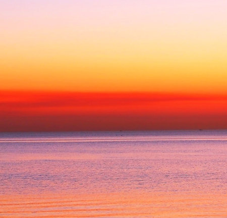 Sunset over the sea with orange and pink colors in the backgroundの写真素材