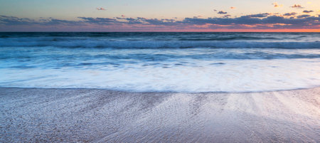 Beautiful sunset on the beach. Panoramic view of the sea and waves.
