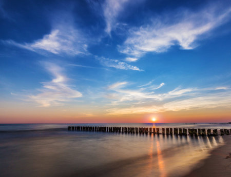 Beautiful sunset over the sea with wooden breakwaters in the foregroundの写真素材