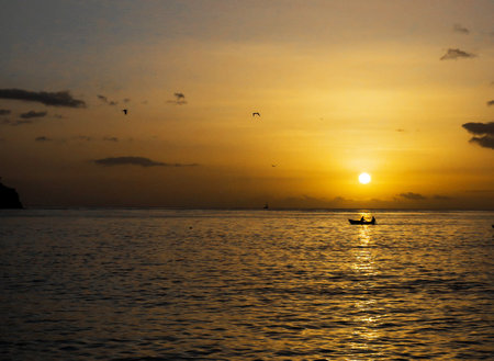 Sunset on the sea with a boat in the foreground and silhouettes of seagulls.の写真素材