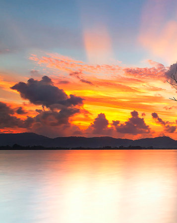 Beautiful sunset on the lake with mountains and clouds, Thailand.