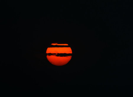 Beautiful sunset in the evening sky with red sun and clouds.の写真素材