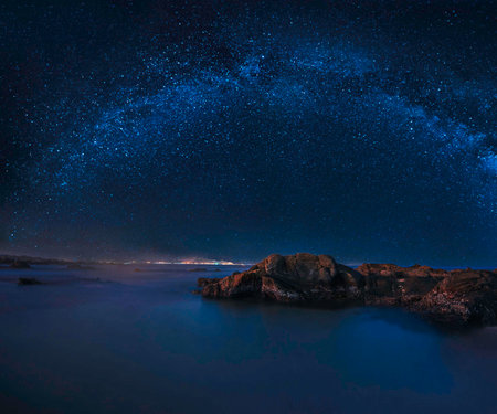 Milky way over the sea at night with rocks and starry sky