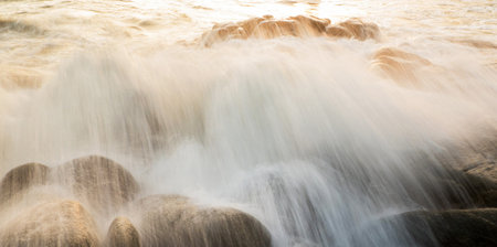 Long exposure of water flowing over rocks at the beach in the evening