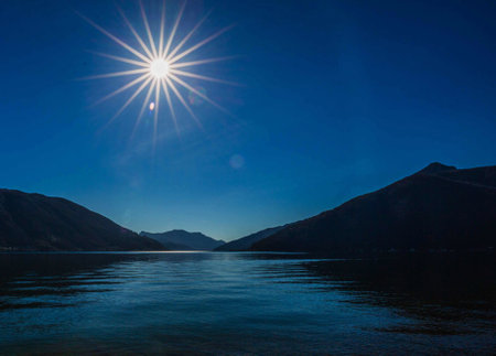 Lake Garda in Italy at sunrise with sun and mountains in the backgroundの写真素材