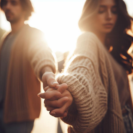 Close up of young couple holding hands and looking at each other while walking outdoorsの素材