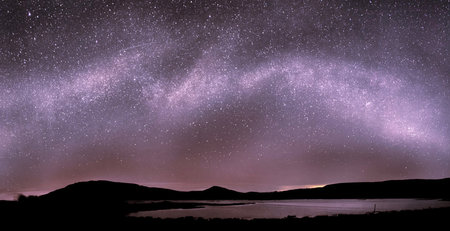 Milky Way over a lake with mountains in the background. Long exposure photograph.