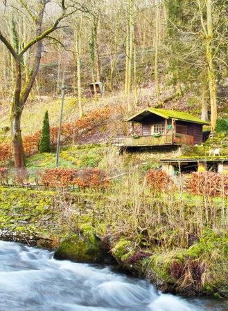 Wooden house on a bank of a mountain river in the forestの写真素材
