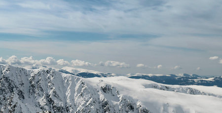 Winter mountains panorama with snow covered alpine peaks and blue sky