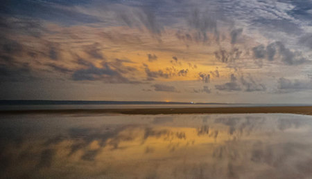 Sunset on the beach with reflection of clouds in the water.