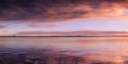 Sunset over the sea with dramatic clouds and reflections in the water