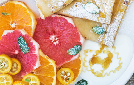 Pancakes with orange, grapefruit and sugar on wooden backgroundの写真素材