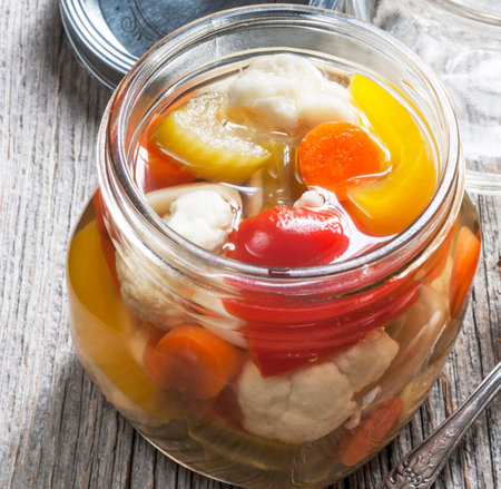 Pickled vegetables in a glass jar on a rustic wooden backgroundの写真素材
