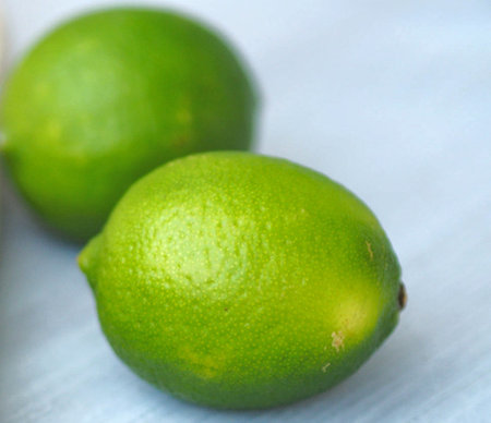Green limes on a blue background. Shallow depth of field.