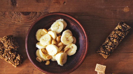 Bowl of homemade granola with banana and nuts on wooden background