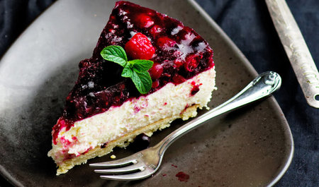 piece of cake with raspberries and mint on a black background