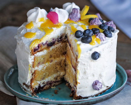 Cake with whipped cream and fresh blueberries on a wooden table