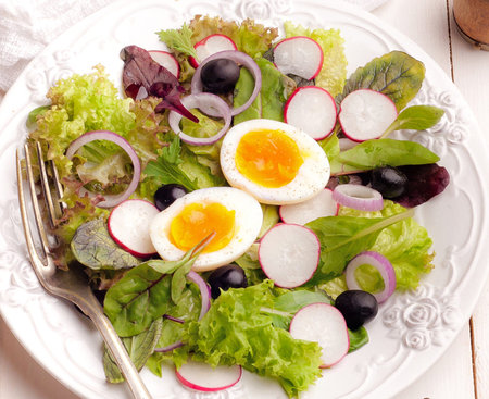 Salad with radish, lettuce, eggs and black olivesの写真素材