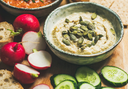 Bowl of hummus with cucumber, radish and pumpkin seedsの写真素材