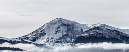 Panoramic view of snow covered mountain tops in the clouds.の写真素材