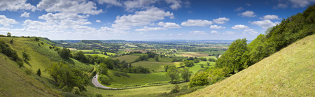 Idyllic rural view of pretty farmland with white fluffy clouds, in the beautiful surroundings of the Cotswolds, England, UK.の写真素材