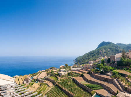 Traditional villa overlooking terraced vineyard and idyllic blue sea, Majorca, Spain.