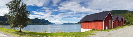 Boat houses overlooking idyllic lakeside view in Norway.の写真素材