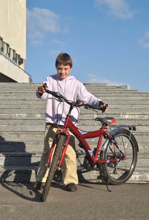 The boy stands at the bicycleの写真素材