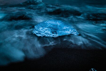 Iceland ice shard block crystal clear on black beach at Jokulsarlon glacier lagoon meltingの写真素材