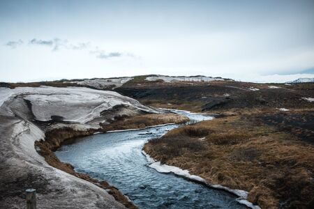 Iceland landscape with river and meadow brown in winter with snow and iceの写真素材