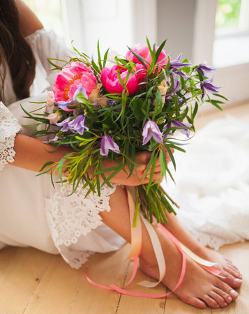 a wedding bouquet with peonies in the hands of the girl who sits, her legs are visibleの写真素材