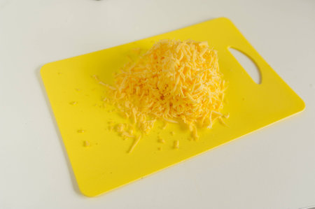 Grated cheese and grater on a plate on the tableの写真素材